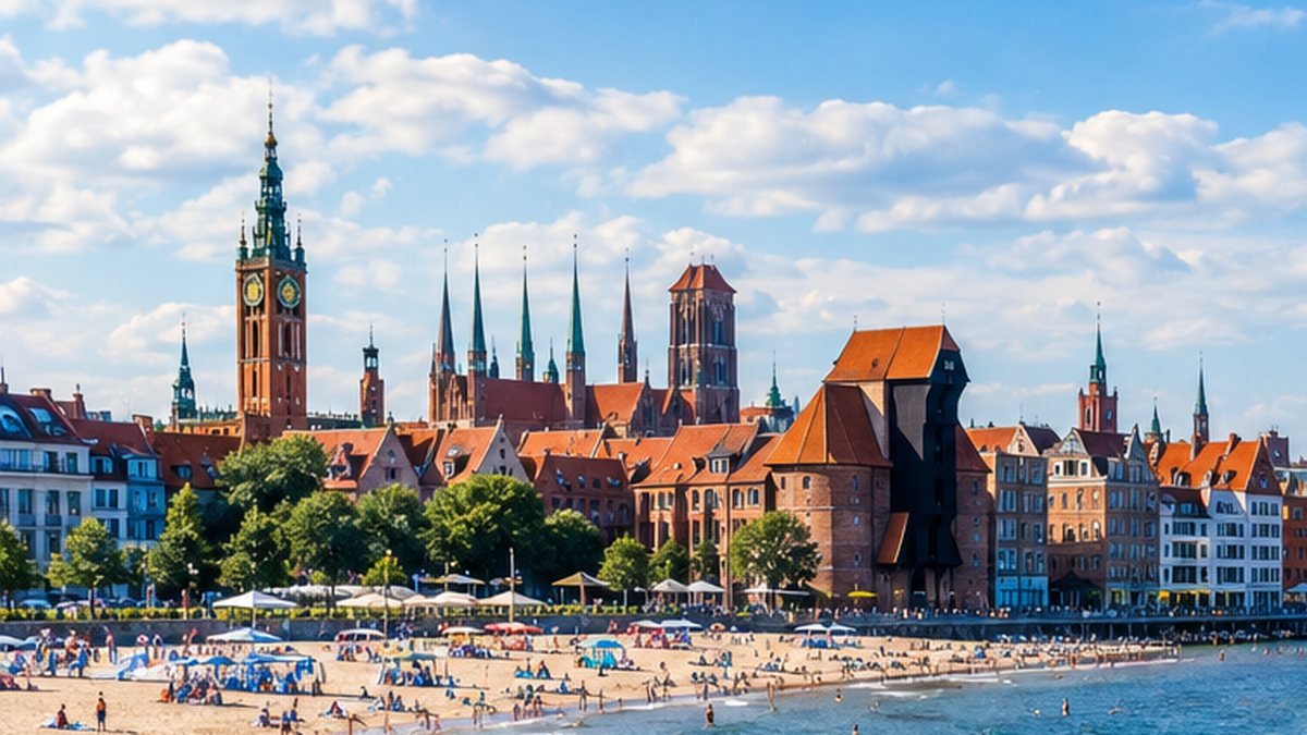 Starówka nad piaszczystą plażą w słoneczny dzień, parasole i ludzie nad wodą